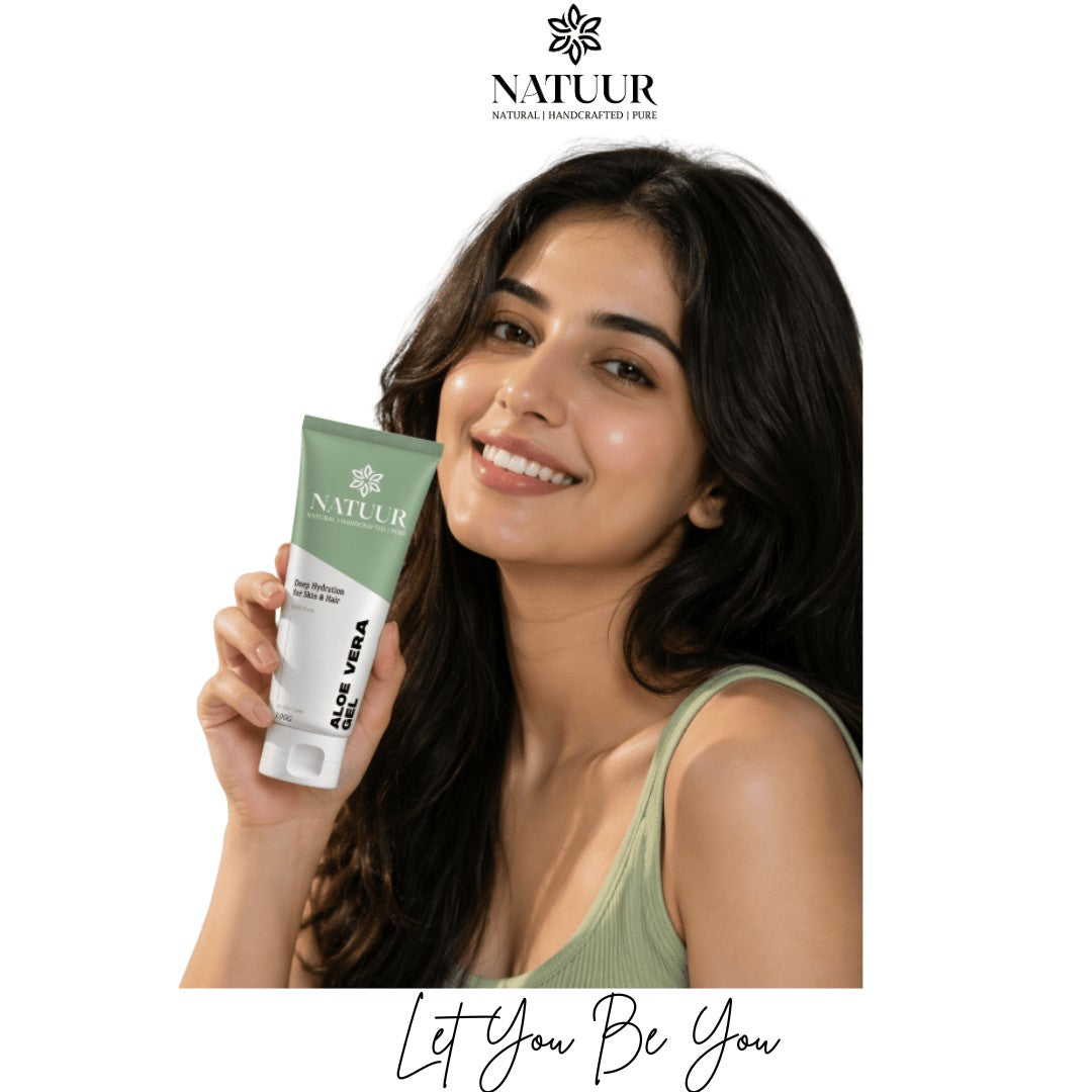 A smiling woman holding a tube of Natuur.in Soothing Aloe Gel for skin and hair hydration against a white background.